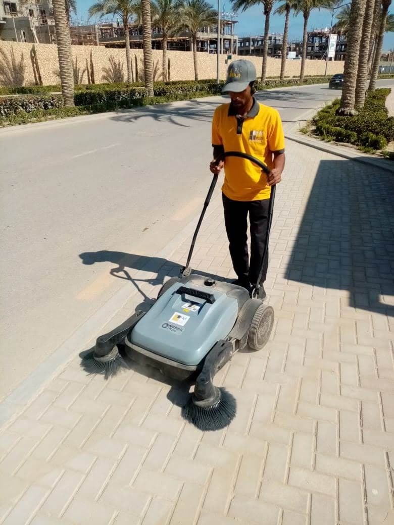 FM+ team member cleaning a walkway with a sweeper at Marassi